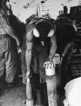Gnr. Mike Longley and Gnr Charlie Hayden, of 104 Battery RAA at Fire Base "Betty" in the ammunition bunker preparing shells for firing.  