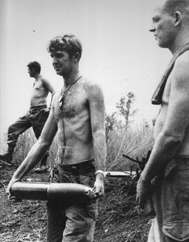 Gnr Jim Dunn, watched by Stg Pete Tilbrook, of 104 Battery RAA,carries a 105mm shell to the gun at Fire Support Base Betty. 