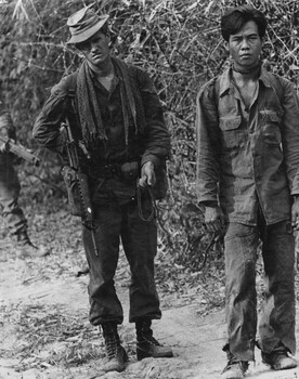 Cpl Gary Mosely keeps a tight reign on a captured NVA/VietCong sapper prisoner.