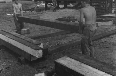 Engineers working in the saw mill at 1st Australian Task Force, stack large beams for bridge construction. 
