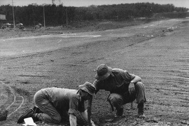 Capt Tony Eaton, the 1st ATF Artillery Intelligence Officer and Sgt Paul Butcher checks the impact area of a NVA/VietCong 107mm rocket for fragments. 