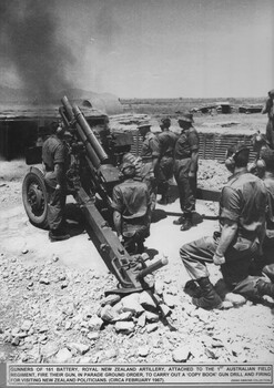 Several soldiers standing and kneeling around a Howitzer