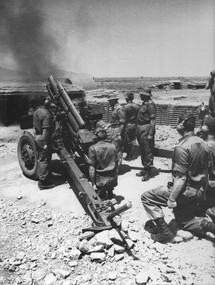 Several soldiers standing and kneeling around a Howitzer