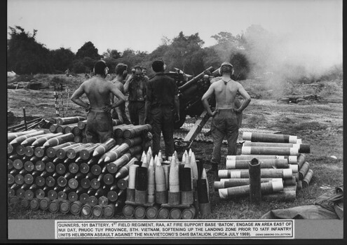 Six soldiers standing amongst artillary on the ground near a howitzer