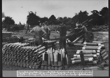 Several soldiers standing amongst artillery near a howitzer.