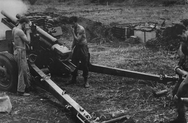 Two soldiers near a howitzer. One has his hands over his ears.