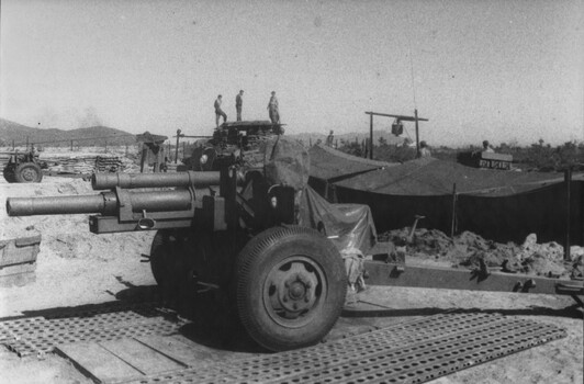 A photograph of a 105mm gun in its bay at a Fire Support Base, at the base of the Nui Thai Vai Mountains. 