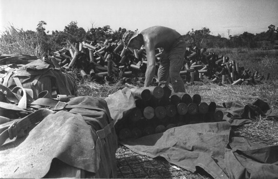 A photograph of a Gunner at the 1st Australian Task Force Base, Nui Dat, Phuoc Tuy Province, sorting 105mm shell casings. 