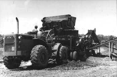 A photograph of Engineers, from 17 Construction Squadron, use a front end loader to deliver rock into a mobile crusher. 