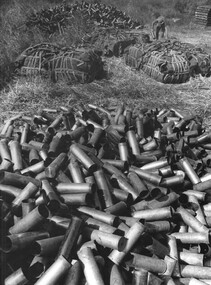 A photograph of a Gunner at 1st Australian Task Force Base, Nui Dat, Phuoc Tuy Province,  sorting 105mm shell casings. 