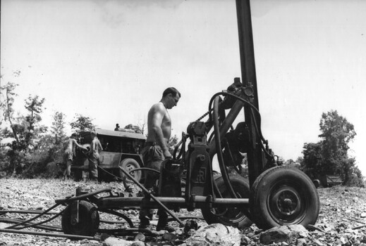 A photograph of Engineers from 17 Construction Squadron preparing the freshly graded road surface for sealing.  