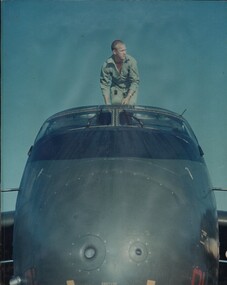 A photograph of the Loadmaster on board an RAAF Caribou transport aircraft carrying out an early morning check. 