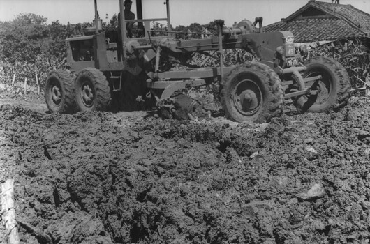 A photograph of Engineers from 17 Construction Squadron grade the road surface for sealing.  