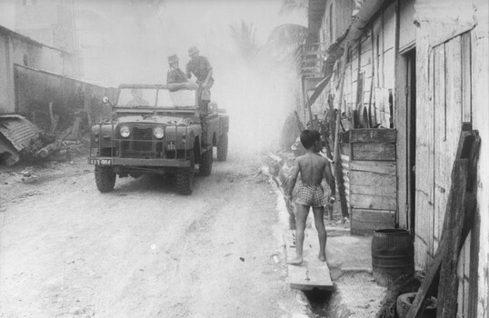 A photograph of Lt Phil Hills and his team driving a landrover towing a mist generator to decontaminate the village of Long Dien. 