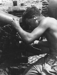 A photograph of a gun crew member of the 103 Battery, reseting his gun during a fire mission in support of infantry mission. 