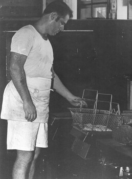 A photograph a cook in the kitchen at the 1st Australian Field Hospital, Vung Tau, preparing some fish patties for deep frying. 