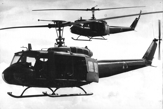 A photograph of two Huey 'slick" helicopters of the 135th Assault Helicopter Company collecting Vietnamese troops operating in the Mekong Delta area. 