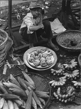 A photograph of a young boy 'Fruit and Nut Seller' winking at the camera, to emulate the act of capturing the photograph. 