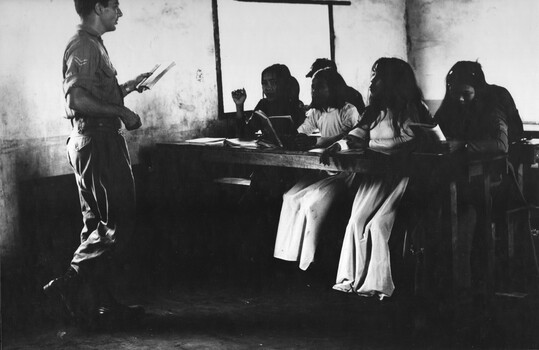 A photograph of a Corporal teacher/linguist with the 1st Australian Civil Affairs Unit, conducting a class in English for Vietnamese girls. 