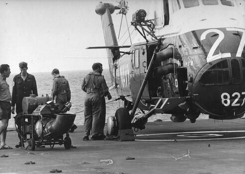 A photograph of the naval ground crew preparing a Sea King helicopter for a Anti-submarine flight around  Vung Tau Ferry HMAS Sydney. 