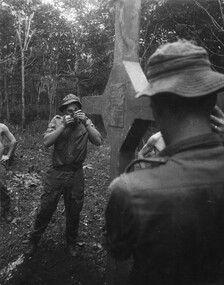 A photograph of Long Tan, Phuoc Tuy Province, A digger from 6th RAR/NZ (ANZAC) Royal Australian Regiment, sites in the cross of remembrance. 