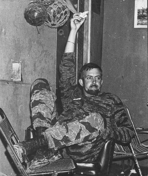 A black and white photograph of Denis Gibbons in camoflague gear taking a rest at the 1 ATF Base Nui Dat, Vietnam.