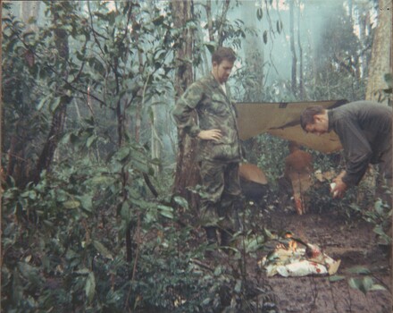 A photograph of Australian United Press International War Correspondent Denis Gibbons, in a night harbour position with members of the 8th Battalion. 