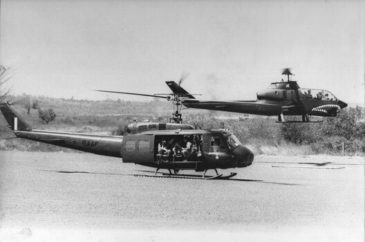 A photograph of a RAAF 'Slick' Huey helicopter at the 1st ATF Base Nui Dat, preparing to lift out a Special Air Services patrol. 