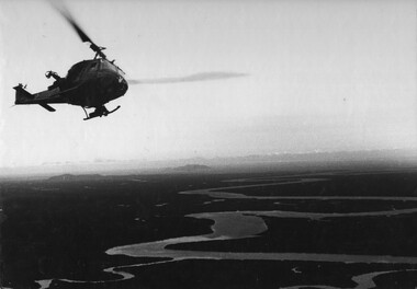 A photograph of a Huey helicopter Gunship from the 1st Platoon 'The Playboys' 334th Armed Helicopter, peeling off to attack sampans entering South Vietnam. 