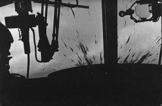 A photograph of a Huey Gunship from the 1st Platoon 334th Armed Helicopter with its windscreen sprayed with mud after firing two rockets. 