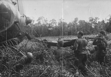 A photograph of a medic aboard the American 'Dustoff' Huey helicopter guiding the makeshift stretcher, containing wounded VietCong. 