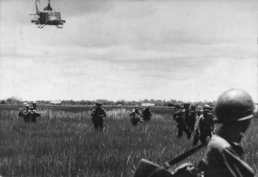 A photograph of the 135th Assault Helicopter Company landing rangers from the Army Of The Republic Of Vietnam into paddy fields. 