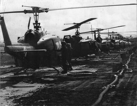 A photograph of Crew members of the 135th Assault Helicopter Company refuel their aircraft. The unit was stationed at Bear Cat, 3 Corps area.