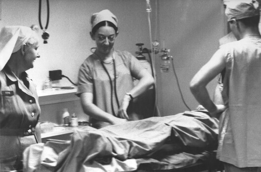 A photograph at the 1st Australian Field Hospital. Matron Nell Espie observes in triage as Fay Lewis and two medics resusitate a wounded Digger. 