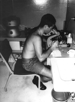 A black and white photograph of a Medic in the 1st Australian Field Hospital Pathology Laboratory checking the growth on culture dishes.