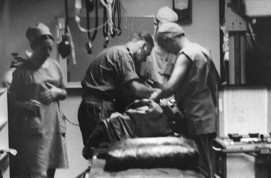 A photo Sister Fay Lewis with a trolley as a medical officer and two medics resusitate a Digger at the 1st Australian Field Hospital. 