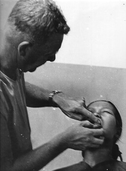 A photograph taken at the 1st Australian Field Hospital, Vung Tau.  A dentist treats a Vietnamese woman who was an employed at Logistic Support Base.