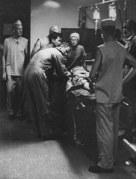 A photograph of Sister June Minchow and medics in the triage at the 1st Australian Field Hospital, Vung Tau preparing a VietCong prisoner for surgery.