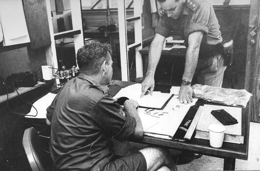 A photograph of Quartermaster Capt John Knowles (standing) at the 1st Australian Field Hospital, Vung Tau talking to his Warrant Officer.