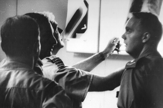 A photograph of  RAAF Wing Commander Alan Breech, assisted by three medical officers in the triage of the 1st Australian Field Hospital, Vung Tau,. 