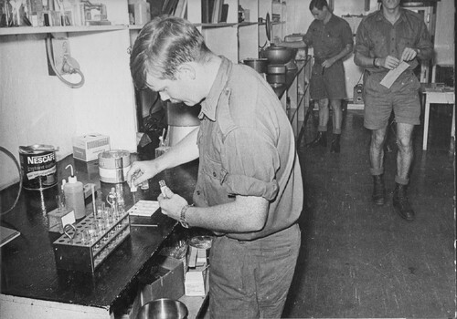 A photograph of Pathology Laboratory technical staff at 1st Australian Field Hospital, Vung Tau, analysing vital specimens from Digger patients. 