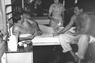 A photo of Red Cross girl Carol Eacott takes down the requirements of two patients during her rounds at the 1st Australian Field Hospital. 