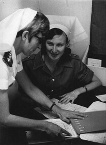 A photograph of ANZAC Nursing Sisters Lt Patricia Ferguson (RAANC), receives the hand over report from Capt Clare Jacobson (RNZANC). 