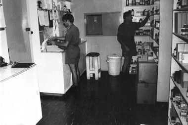 A photograph of Pharmacist Lt Roger Nation prepares prescriptions for patients in the hospital while a pharmacy assistant collects the drugs to be issued.