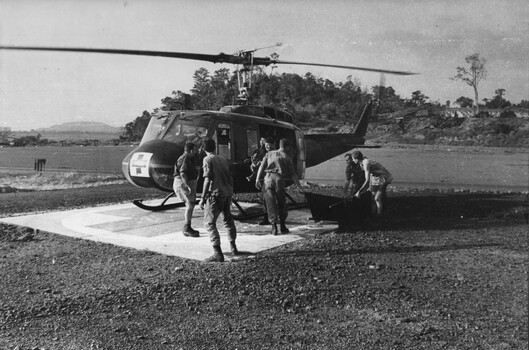 A photograph of Medics and Intelligence Officers meet and unload an American Dustoff medical evacuation helicopter bringing wounded NVA/VietCong. 