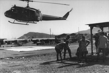 A photograph at 1st Australian Field Hospital, Medics Ron Gillespie and Tony Green turn to avoid the rotor wash from the incoming "Dustoff". 