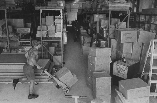 A photograph of Diggers in  the Quartermasters Store at 1st Australian Field Hospital sort and transport stores to their respective area ready for stacking. 