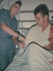 A photograph of Lt Terrie Roche changes the dressing on Sapper Bruce Bevan at the 8th Field Ambulance Hospital, Vung Tau, South Vietnam. 