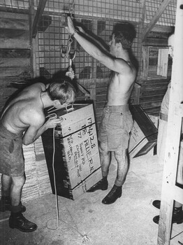 A photograph at 1st Australian Field Hospital Medic, Private Ron Allie's personal trunk is weighed in preparation for return to Australia by stores personnel. 