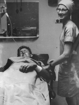 A photo of Sr June Minchow is quietly amused by the expression of a Digger in the triage at the 1st Australian Field Hospital. 